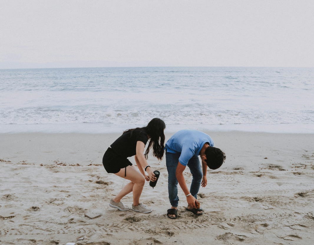 Two friends picking up sandals on Bucer&iacute;as beach in Mexico, enjoying a relaxing day by the sea.